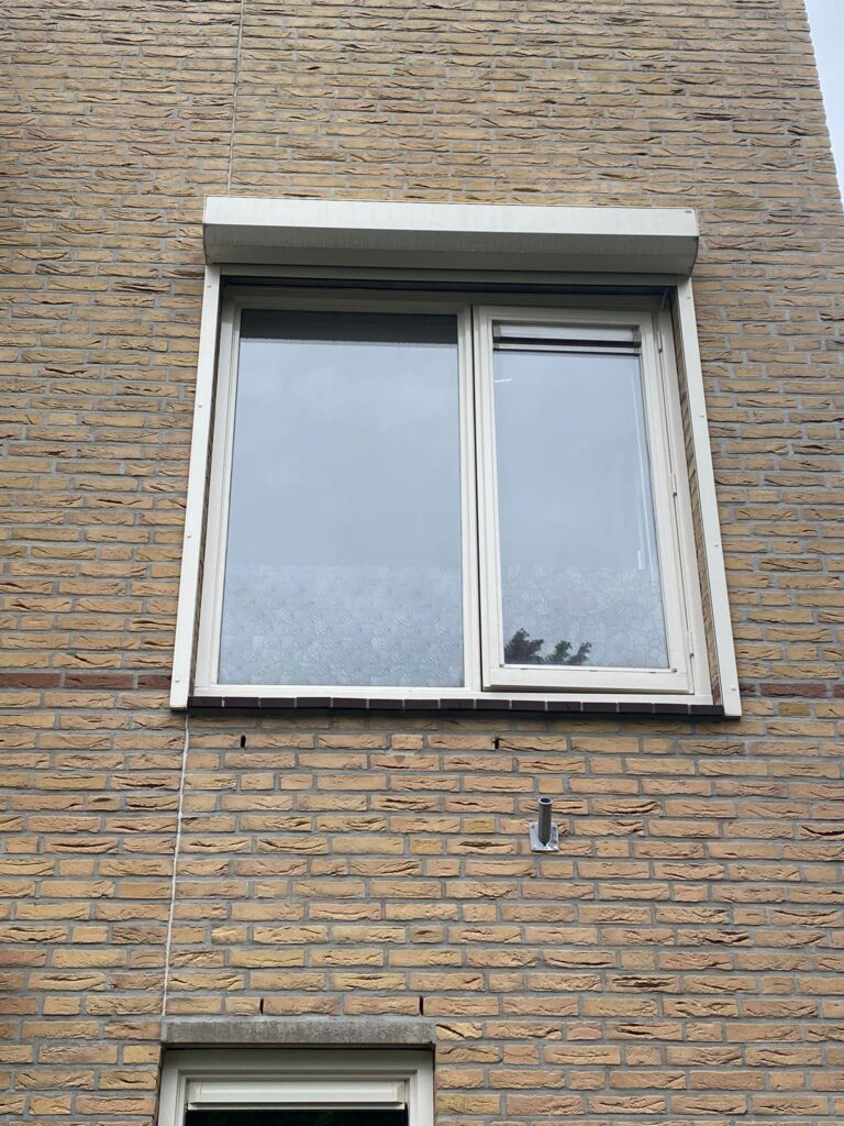 Verouderd raamkozijn op de bovenste verdieping voor het project in Wateringen