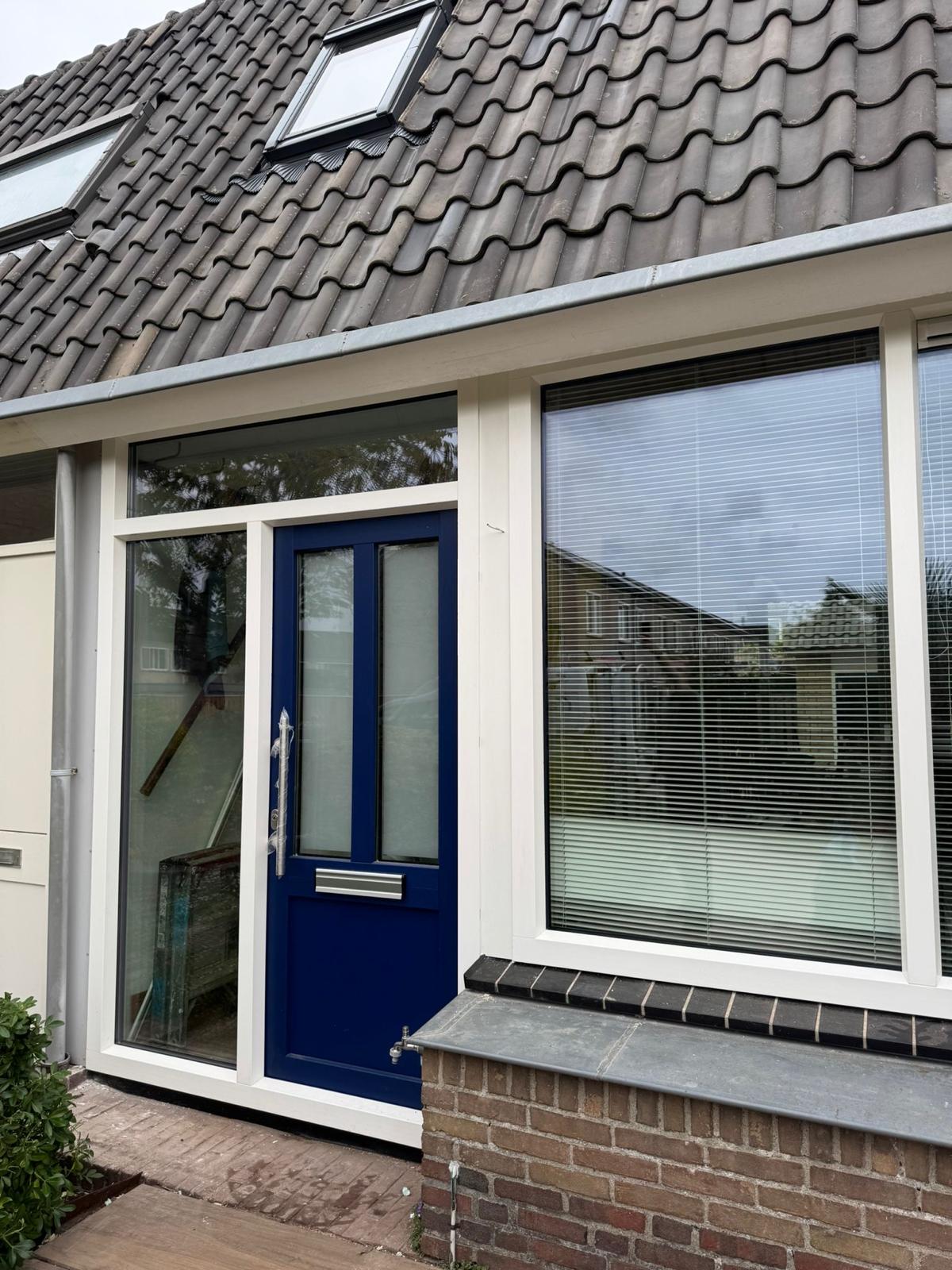 Blauwe kunststof voordeur met zijlicht en kunststof kozijnen geplaatst in woning