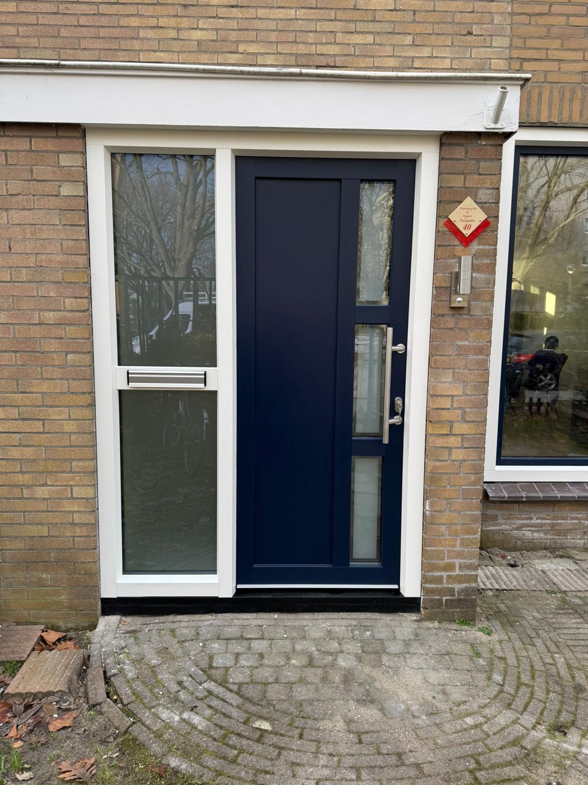Donkerblauwe kunststof voordeur met zijlicht en kozijn geplaatst in bestaande woning