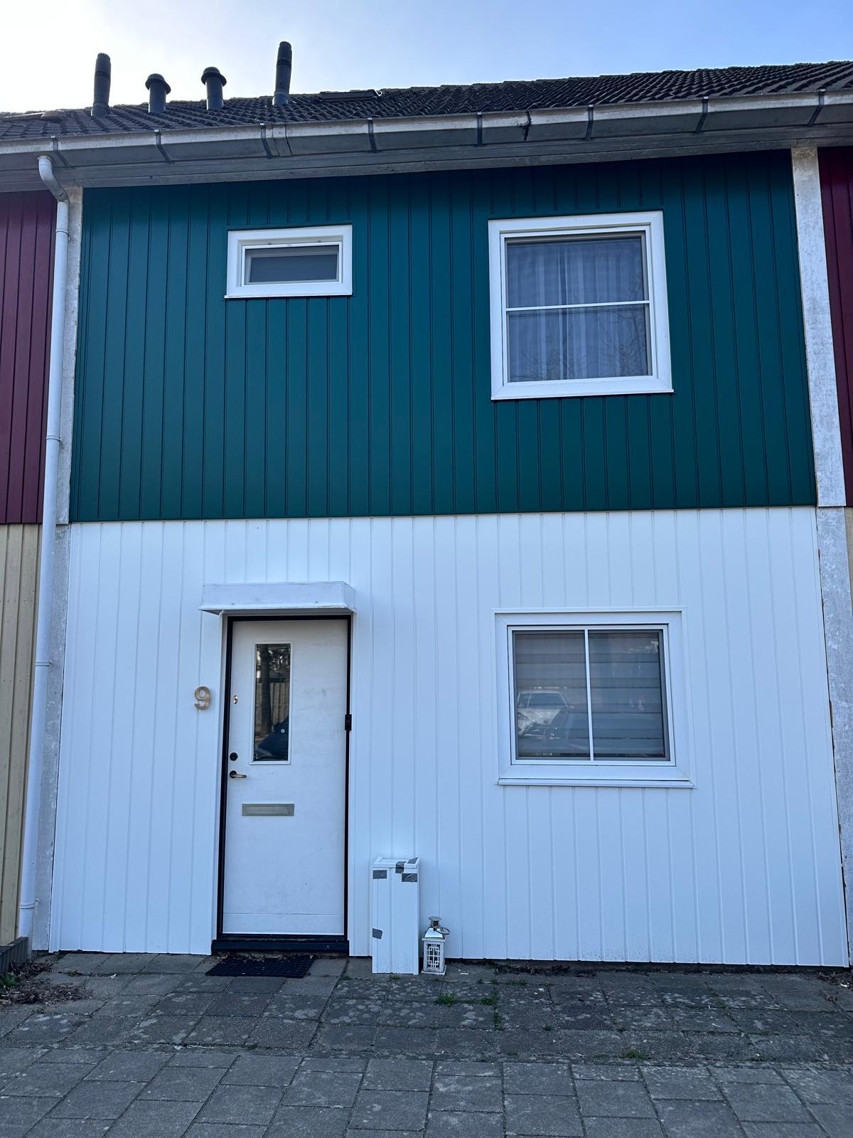 Woning met groene en witte kunststof gevelbekleding na gevelrenovatie