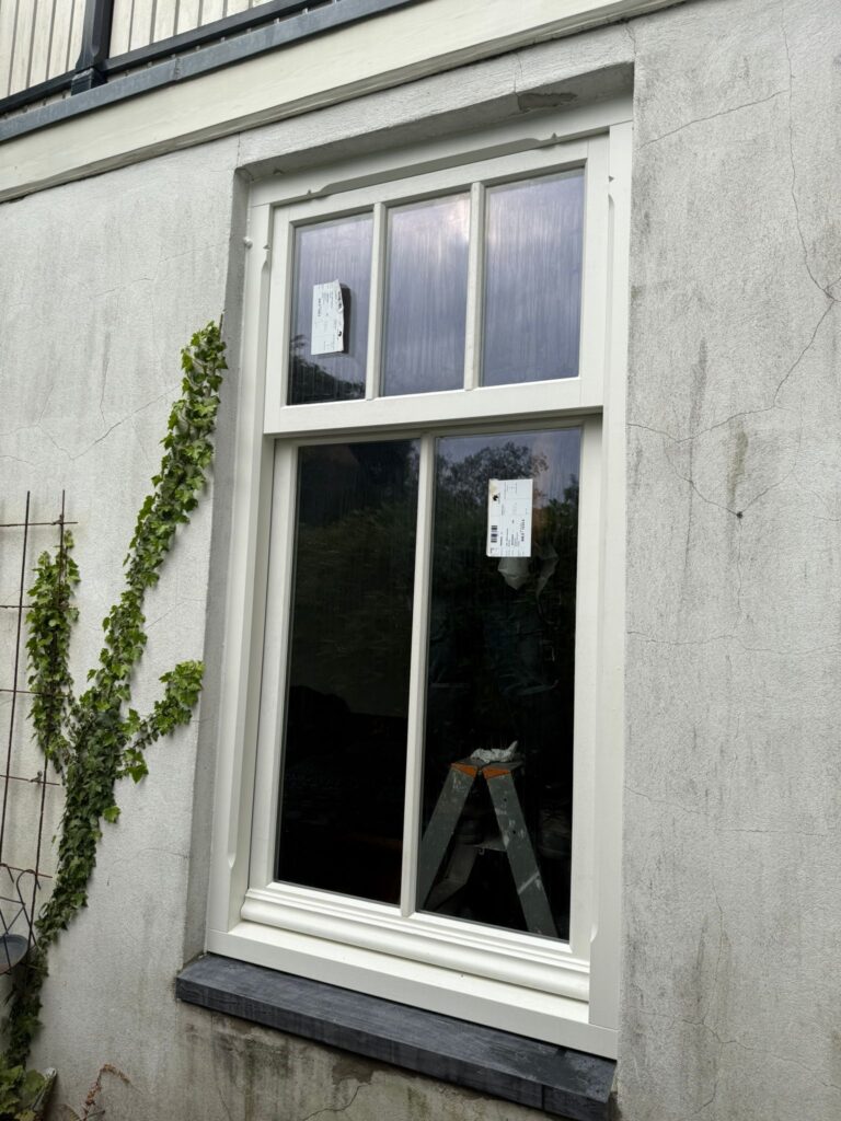 Houten kozijn met klassieke profilering geplaatst in bestaande gevel, passend bij traditionele woningstijl