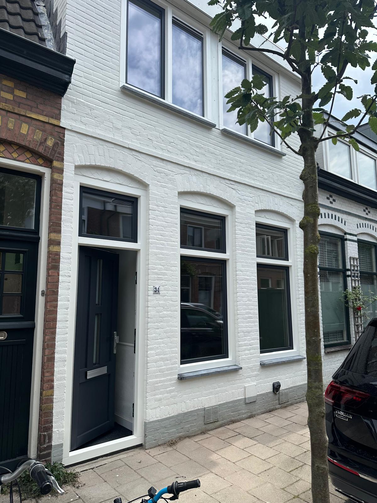 Voorzijde van woning met nieuwe kunststof kozijnen en moderne voordeur in houtlook afwerking