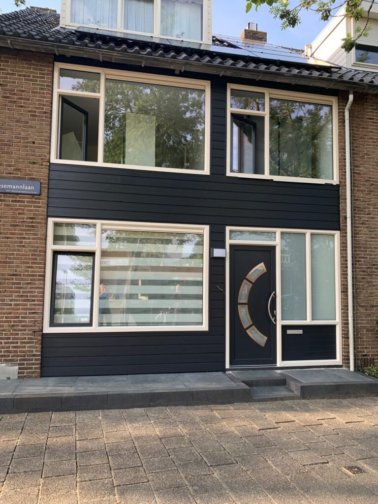 Donkere kunststof gevelbekleding met moderne kozijnen bij gerenoveerde woning