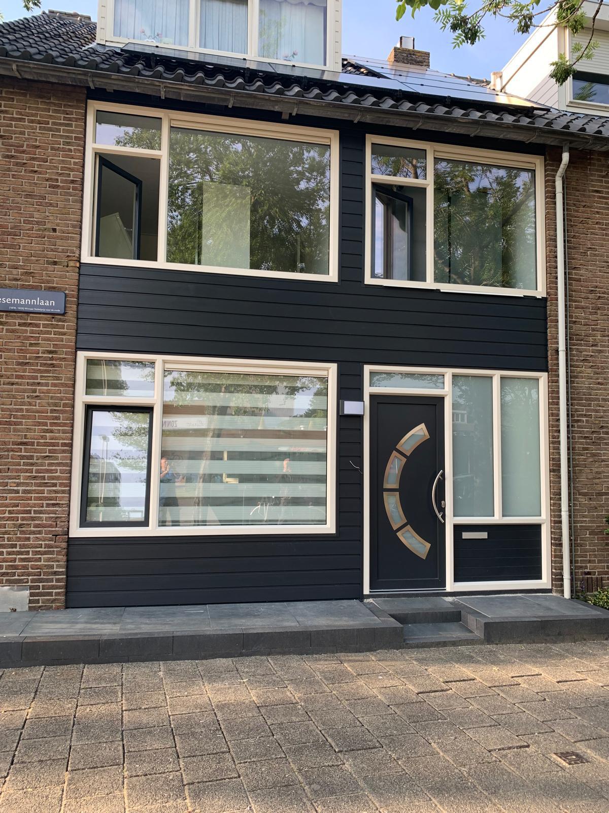 Donkere kunststof gevelbekleding met moderne kozijnen bij gerenoveerde woning