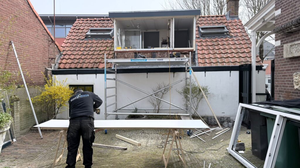 Monteur bezig met renovatie van dakkapel en montage van nieuwe gevelbekleding.