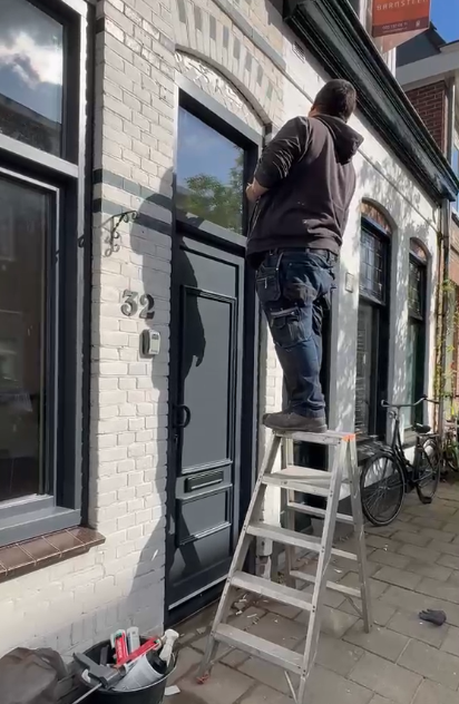 Monteur plaatst nieuwe antraciet kunststof voordeur in klassieke woninggevel