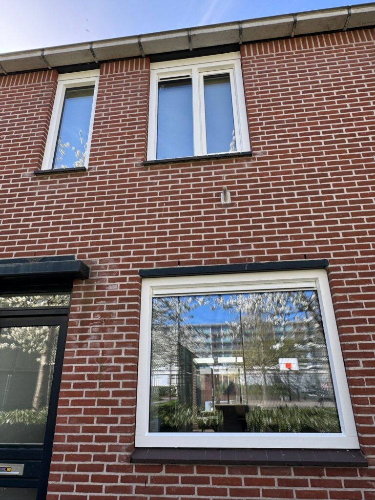 Nieuwe witte kunststof kozijnen op de eerste verdieping van een bakstenen woning