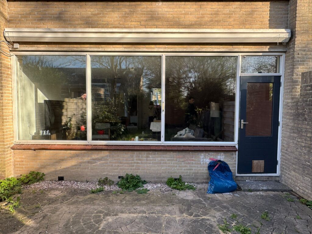 Oude achterpui met verouderde kozijnen en achterdeur vóór vervanging