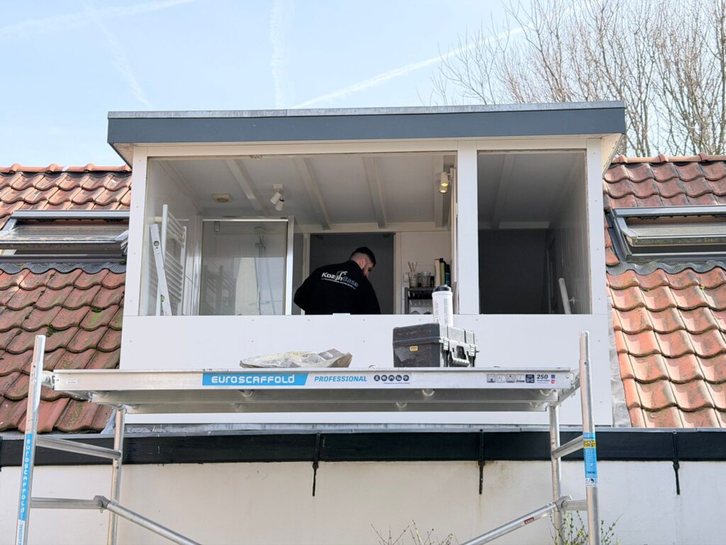 Oude dakkapel tijdens renovatie waarbij bestaande kozijnen en gevelbekleding worden verwijderd.