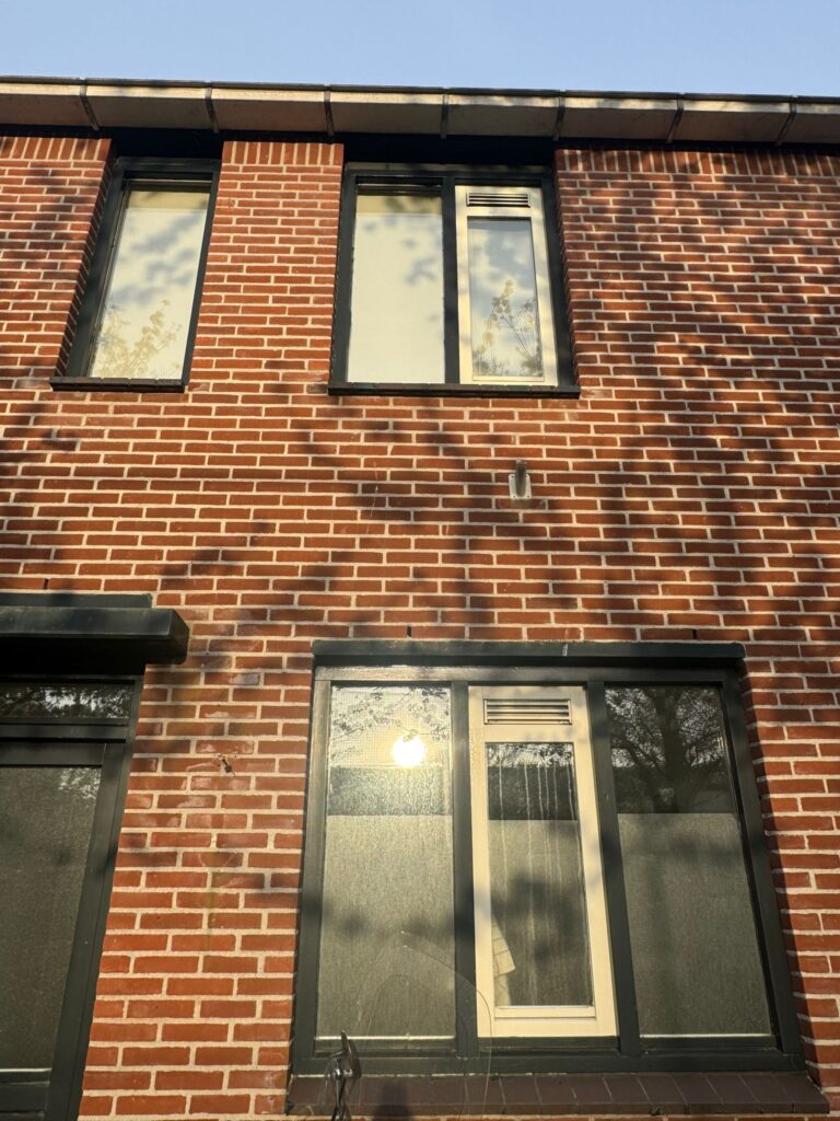 Oude kozijnen aan de voorgevel van een woning vóór vervanging door kunststof kozijnen