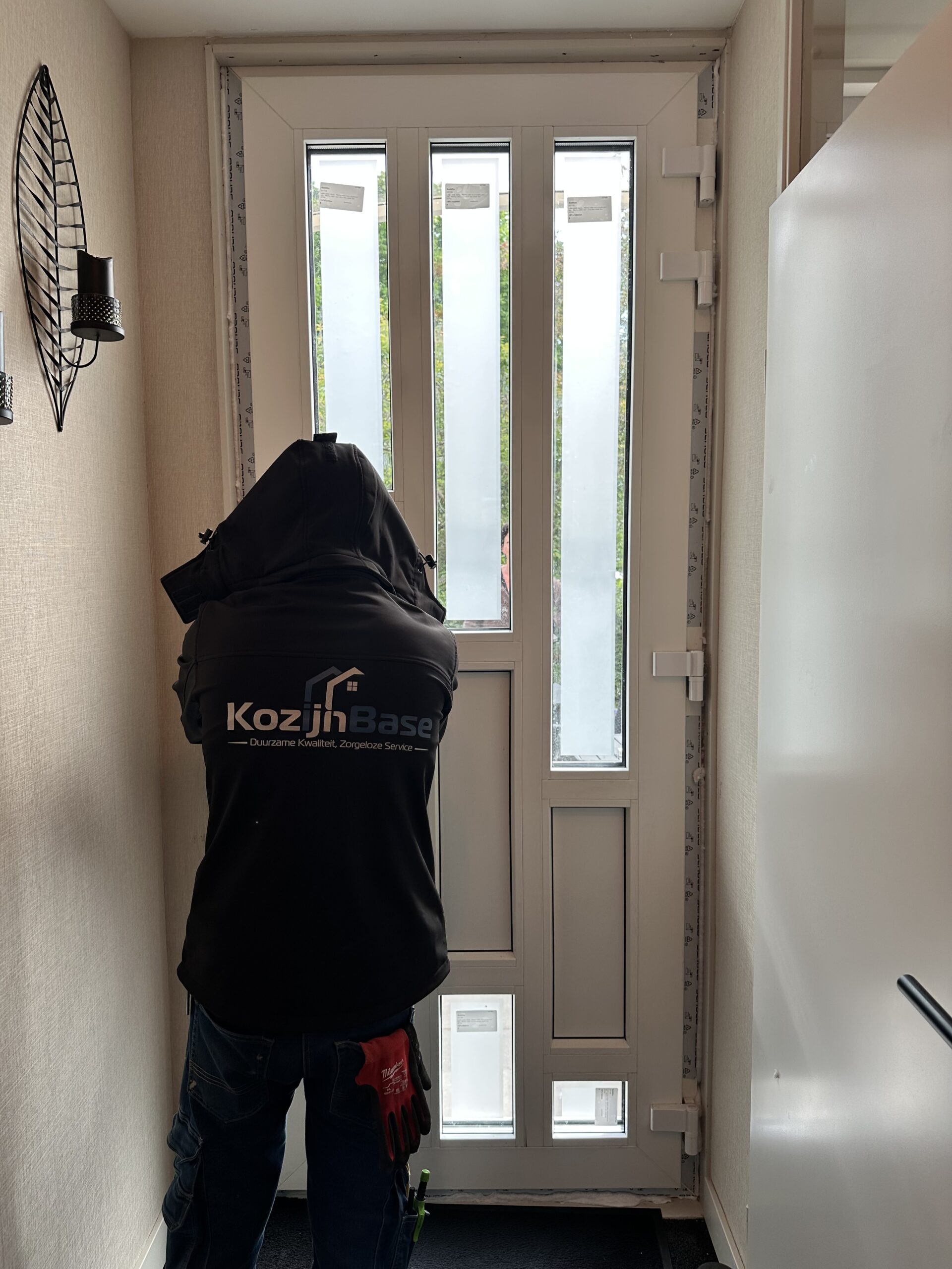 Werkzaam door geheel Haarlem, medewerker bezig met deur plaatsen