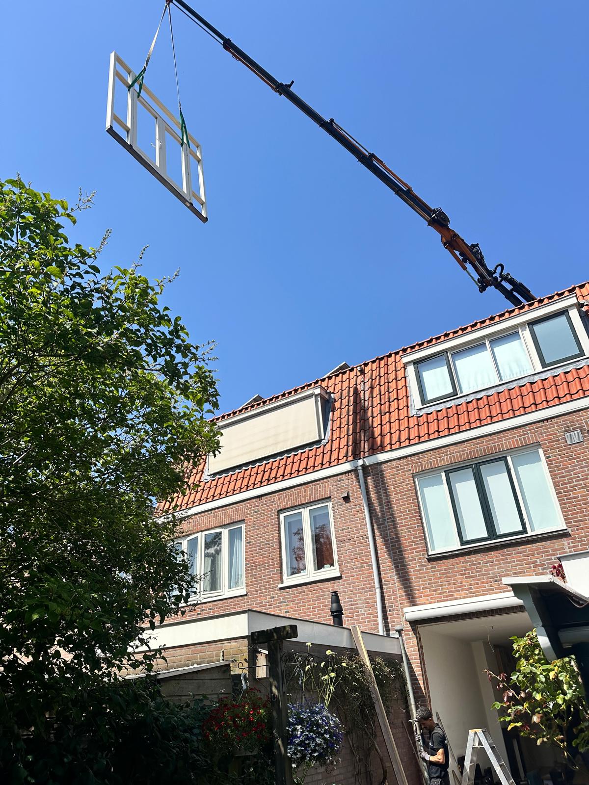 Nieuwe hardhouten pui met een kraan naar de achterzijde van de woning gehesen