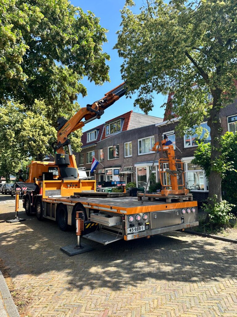 Autolaadkraan opgesteld voor het plaatsen van een hardhouten pui in Haarlem